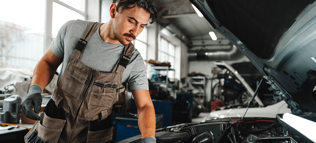 Un mecánico revisando las bujías de un turismo.