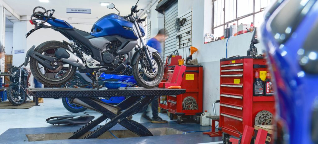 Taller mecánico de motos con una motocicleta azul haciendo la revisión