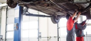 Dos mecánicos revisan los bajos de un coche