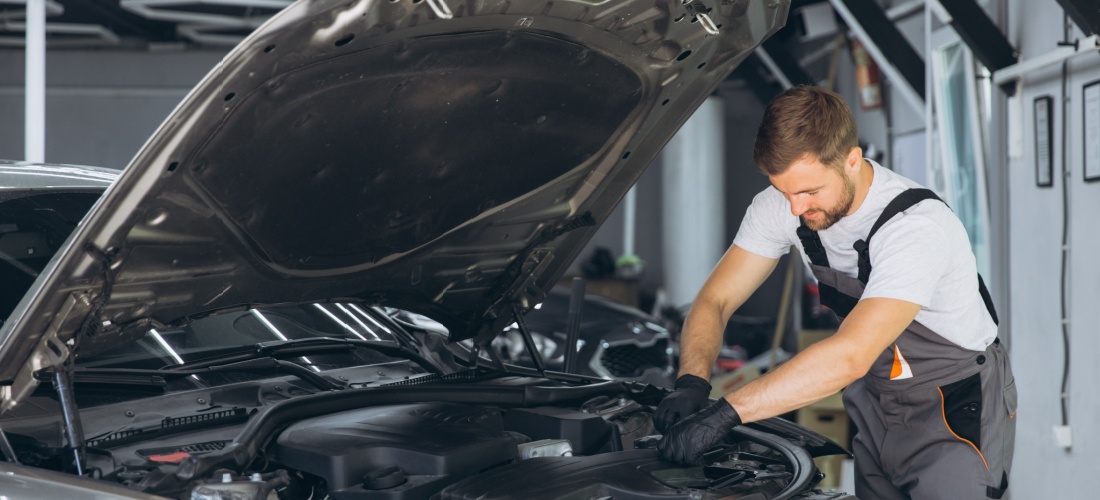 Mecánico joven inspecciona el motor de un coche