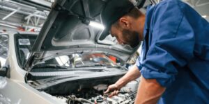 Mecánico con gorra arregla un fallo en un motor de un coche