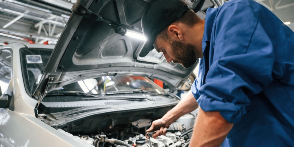 Mecánico con gorra arregla un fallo en un motor de un coche