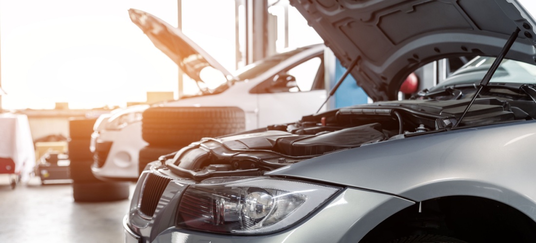 Dos coches con el capó abierto en el taller