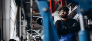 Mecánico con los brazos cruzados apoyado en una autocaravana se niega a realizar una reparación.