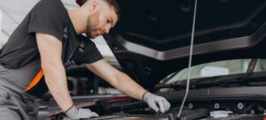 Mecánico rubio revisa el motor de un coche en un taller