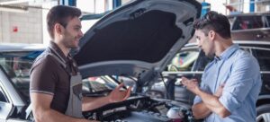 Mecánico hablando con un cliente sobre la reparación de su coche